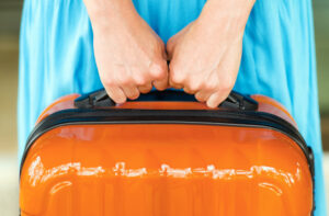 Woman in blue dress holding orange suitcase