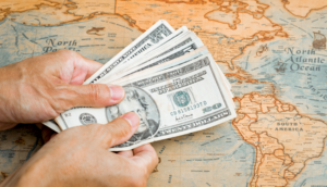 Hand with american money over a map