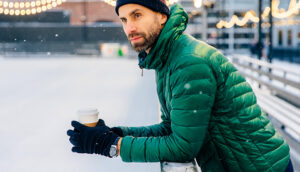 man wearing a puffy jacket and holding a coffee