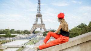 Woman looks out at the Eiffel Tower while wearing a red beret.
