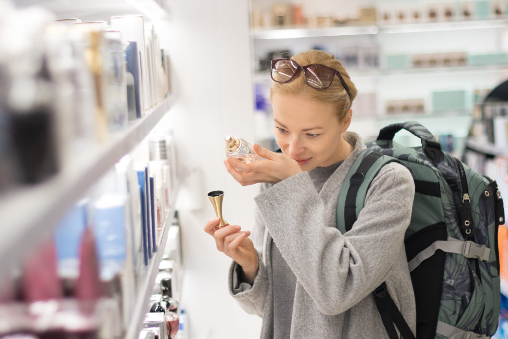 Woman smelling perfume in an airport duty free store