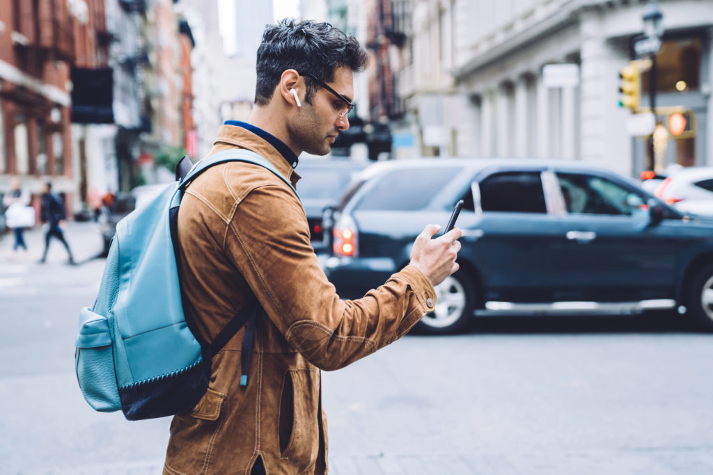 Man looking at phone crossing the street