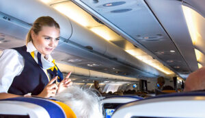 flight attendant speaking with passengers on flight plane; RUBEN M RAMOS/Shutterstock