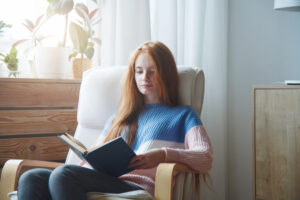 A Woman Reads a Book in a Chair While Self-Isolating