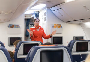 Flight attendant demonstrates where exits are located on flight