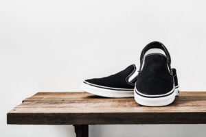 Still life of black slip-on shoes on a wooden shelf