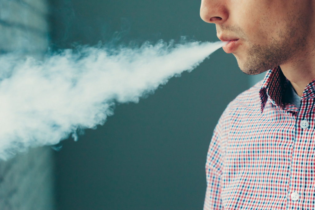 Man blowing vape cloud from e-cigarette