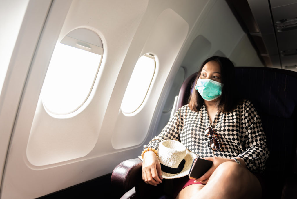 Woman sitting on airplane wearing a face mask