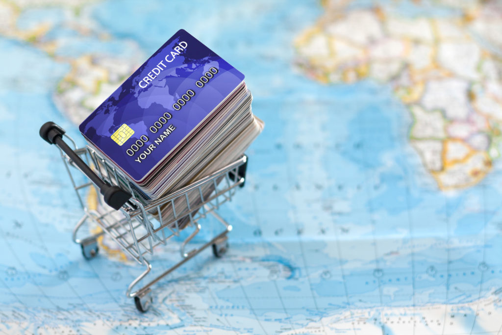 Small cart filled with credit cards on world map