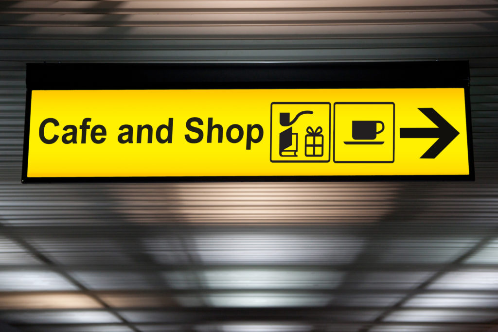 A sign at an airport for the cafe and shops