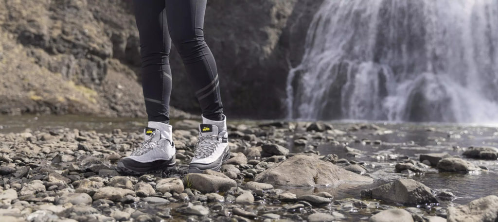 Person walking in hiking boots across a rocky river bed in Iceland