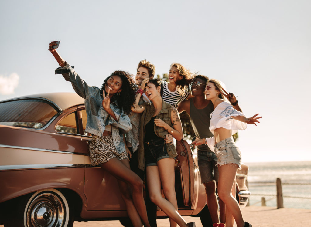 Group of friends taking a selfie by a car