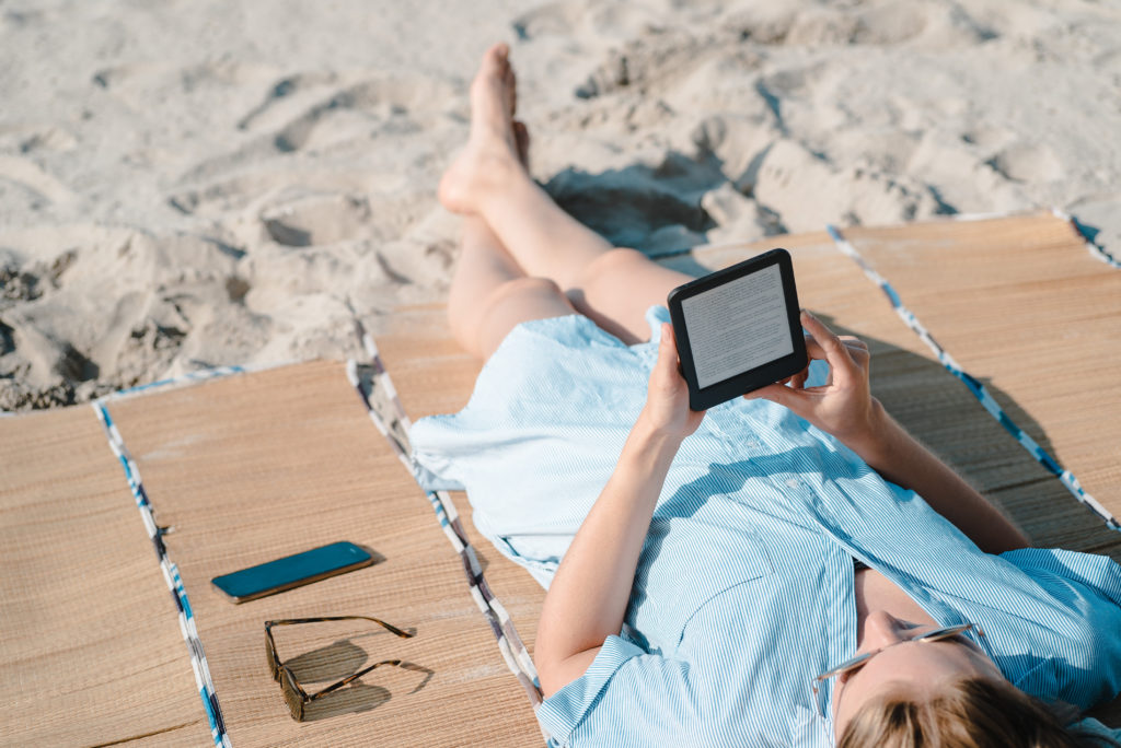 Woman reading on e-reader on the beach