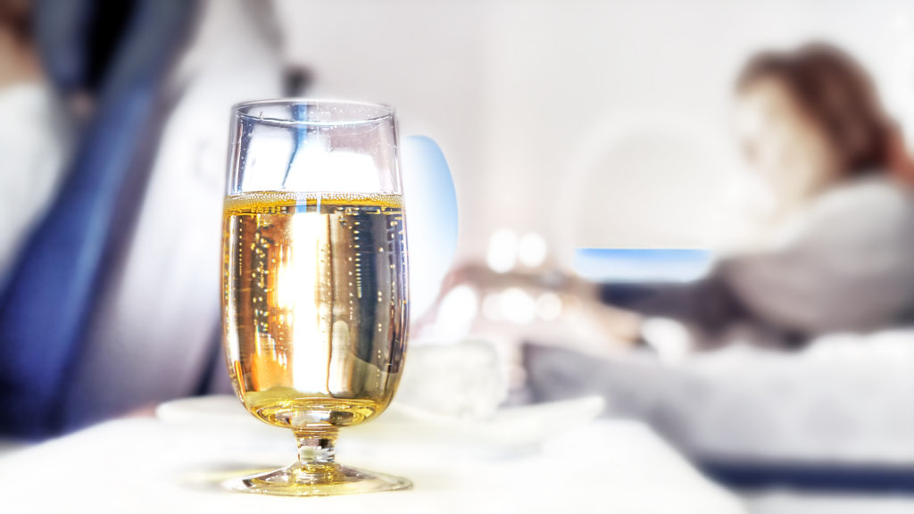 A glass of champagne on an airplane tray table