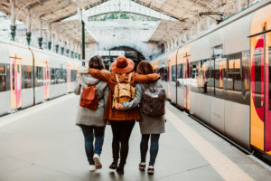 Three friends with their arms around each other, waiting for the train in Porto, Portugal
