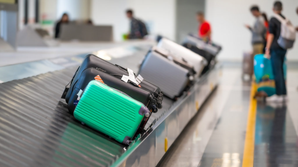 Luggage on a luggage carousel with people waiting