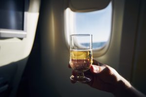 Person holding glass of champagne in front of airplane window