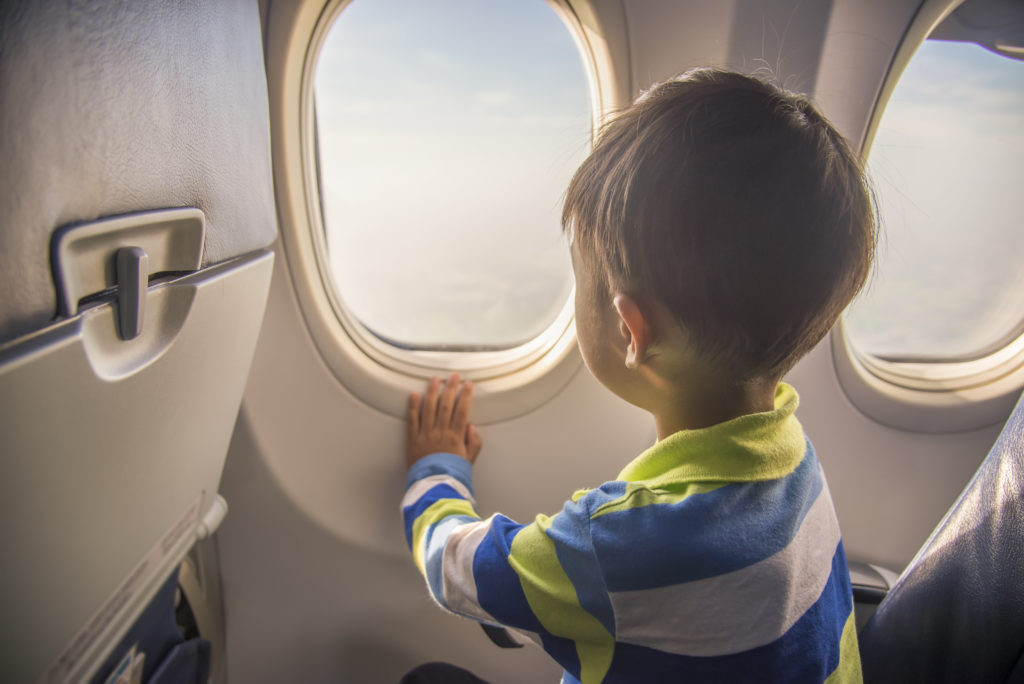 Little boy looking out the window seat of an airplane