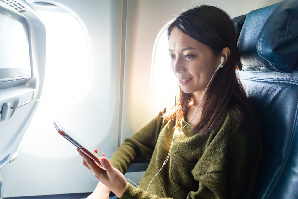 Woman watching a program on her smartphone on an airplane
