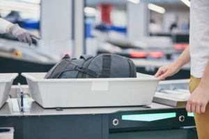 Person placing items in security bin at the airport