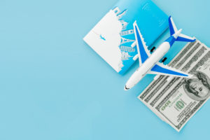 Airplane figurine, cash, and a passport book on a blue background