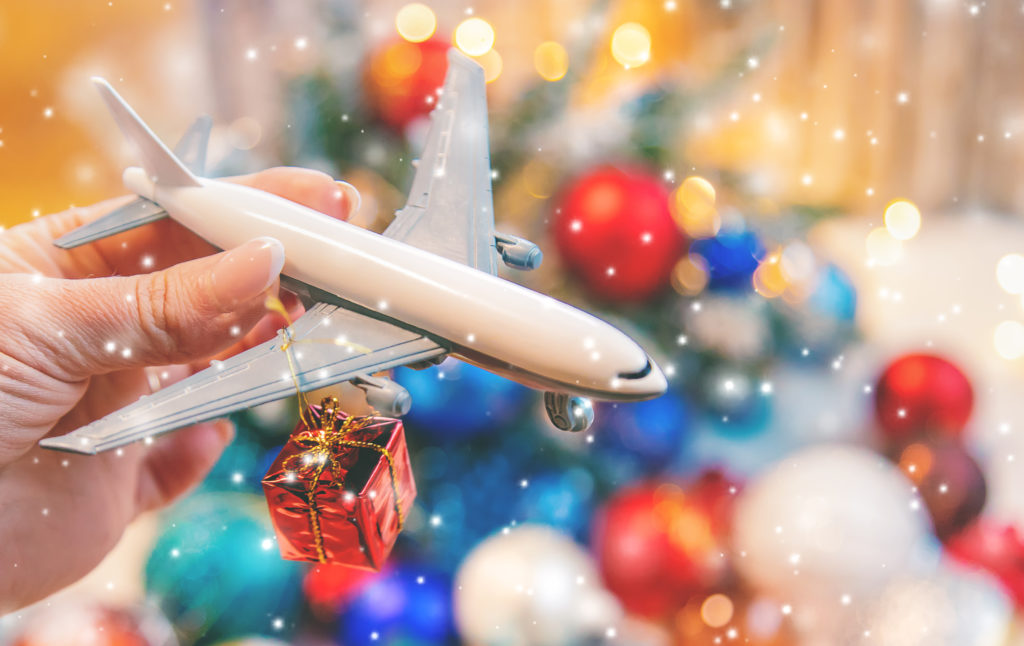 Person holding a model plane in front of a Christmas background