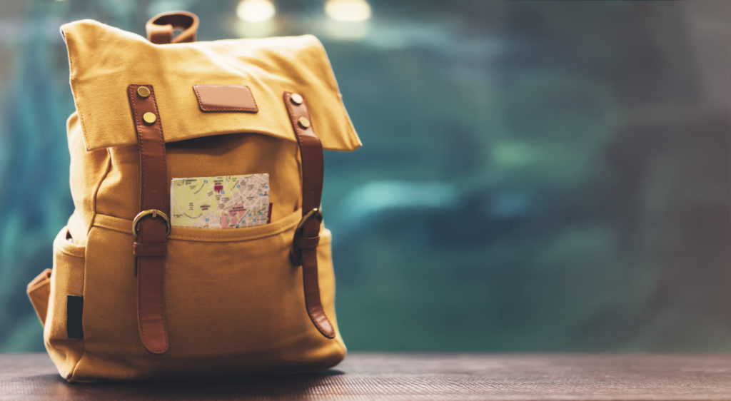 Yellow backpack with map sticking out of one pocket on a wood table
