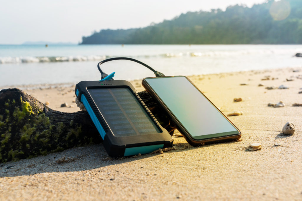 Smartphone plugged into a solar powered charger on the beach