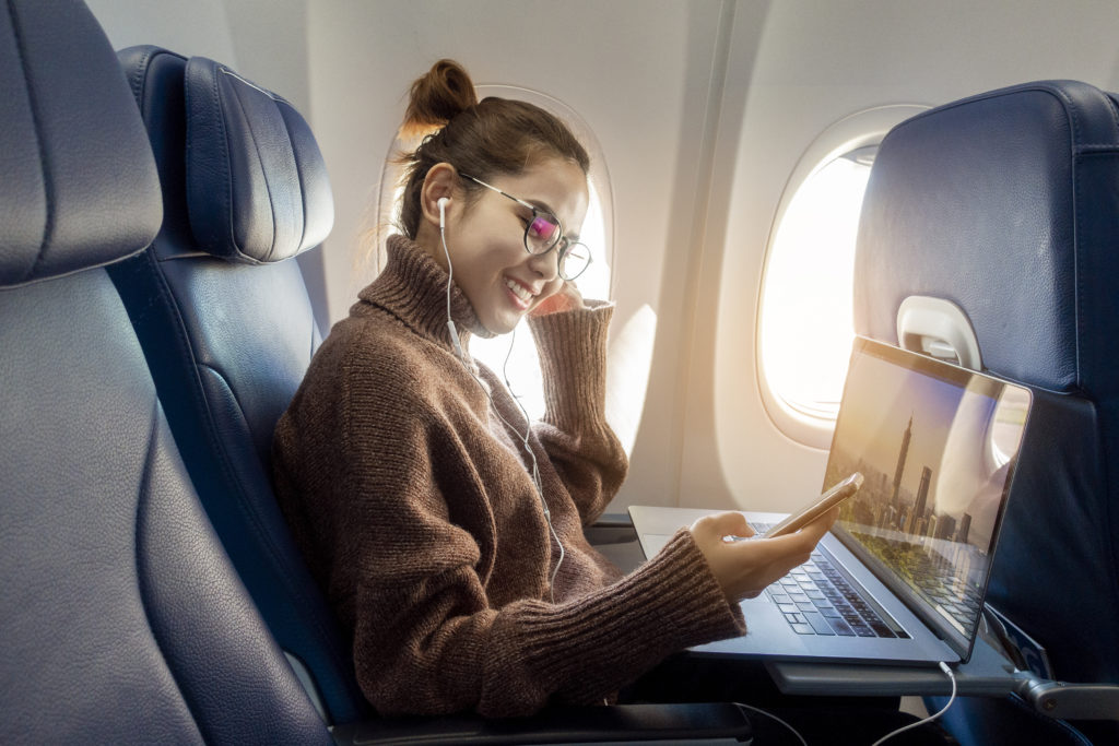 Person using phone and laptop on plane