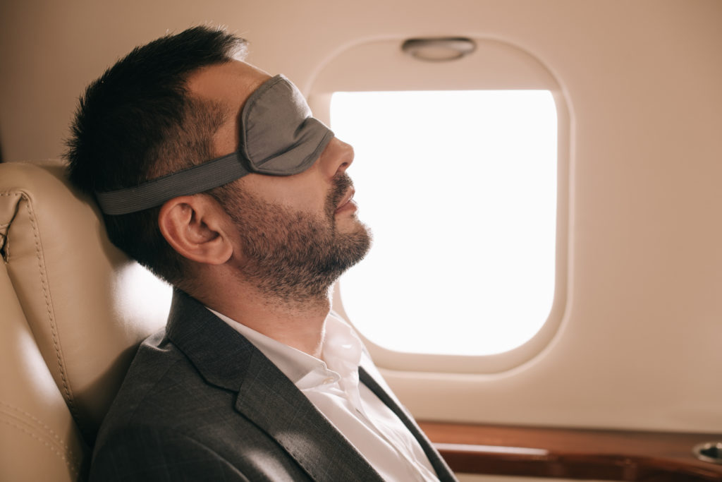 Person sleeping on plane with eye mask