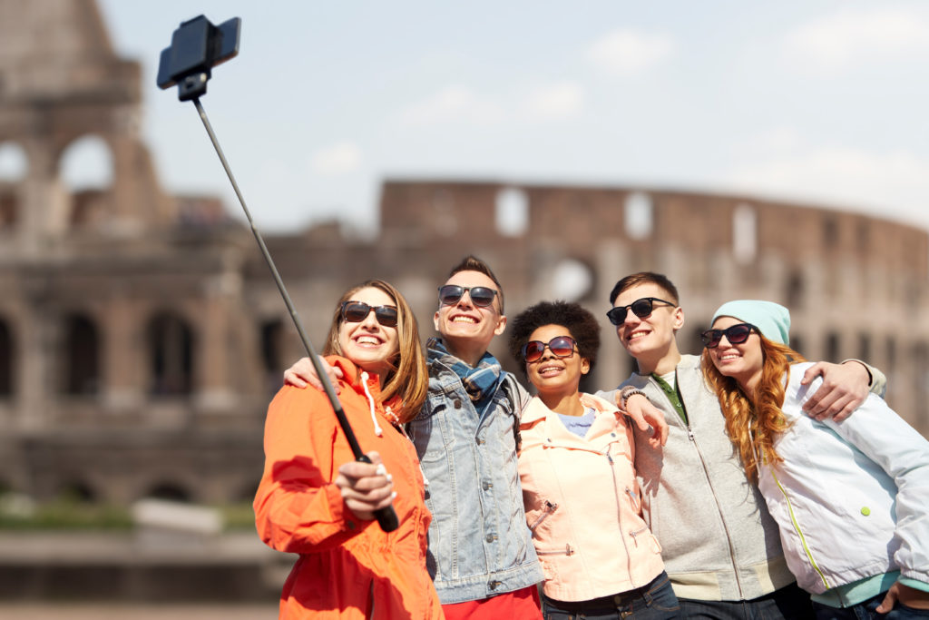 Group of friends taking a photo with a selfie stick in front of the Colosseum 