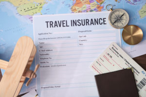 Travel insurance papers on a map with various travel items surrounding them