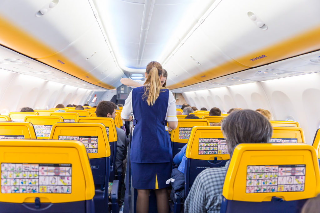 Flight attendant walking up aisle of Ryanair plane cabin