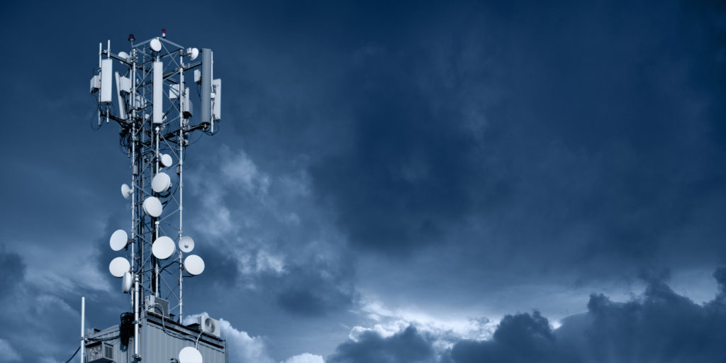 5G transmitter tower on backdrop of dark sky