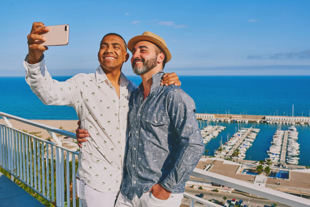 Couple posing for selfie photo in front of a marina full of boats
