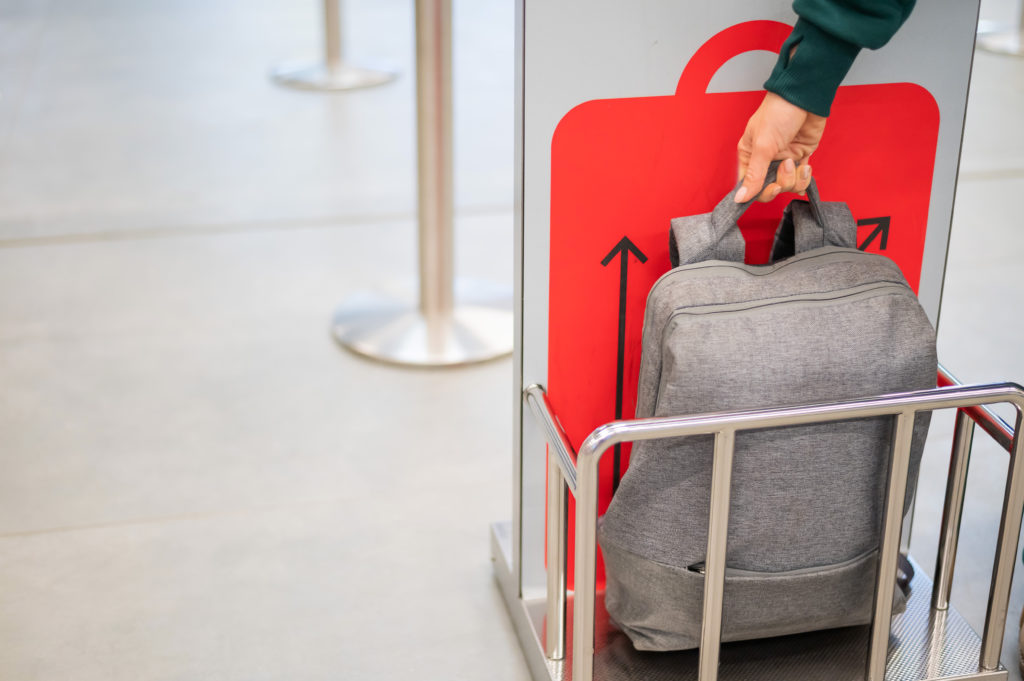 Person checking their carry-on luggage in a metal cart to make sure it fits the airline size maximum